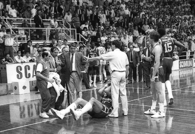 Meneghin (Philips), colpito da una moneta alla testa, è a terra, soccorso dal medico e dal massaggiatore della Scavolini. Si vede tra i soccorritori anche Massimo Cosmelli, direttore sportivo Scavolini. D'Antoni e McAdoo sono increduli spettatori. Cappellari (GM Philips) e Faina (Vice allenatore Philips) stanno accorrendo. All'ingresso degli spogliatoi i giocatori delle due squadre si voltano a vedere la scena e si scorge King (Philips) e Magnifico (Scavolini).